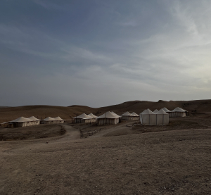 Zeltlager in der W&uuml;ste bei Marrakesch, umgeben von sandigen H&uuml;geln unter bew&ouml;lktem Himmel.