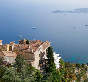 Blick von einer Anh&ouml;he auf H&auml;user mit Terrakottad&auml;chern an der C&ocirc;te d&rsquo;Azur und das tiefblaue Mittelmeer.