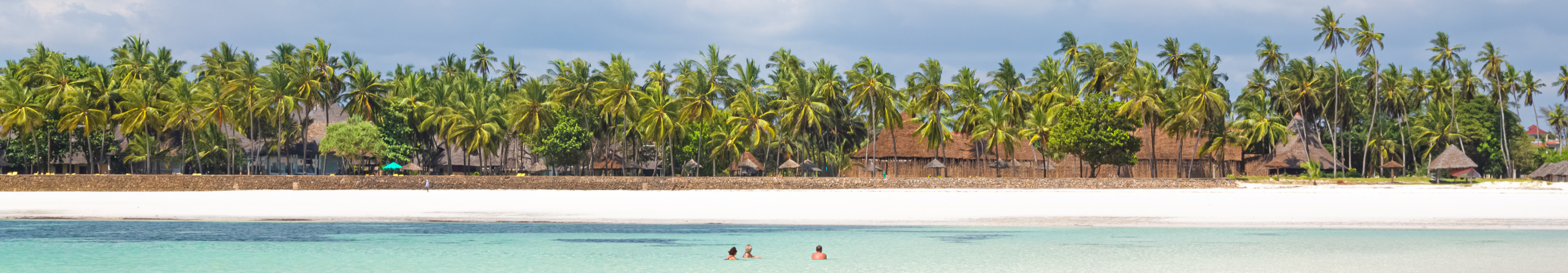 Diani Beach in Kenia mit feinem weißen Sand, klarem Wasser und Palmen entlang des Ufers.