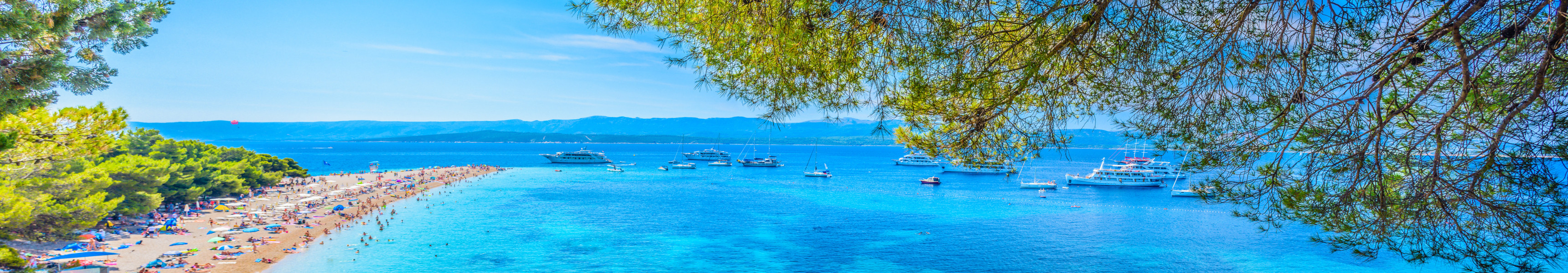 Strand Zlatni Rat auf der Insel Brač in Kroatien, eine lange Landzunge mit feinem Sand, t&uuml;rkisfarbenem Wasser und Booten im Hintergrund.