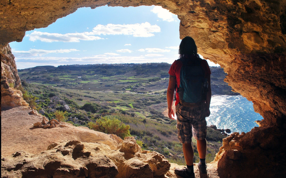 Mann steht auf einem Berg auf der Nachbarinsel Gozo mit Ausblick