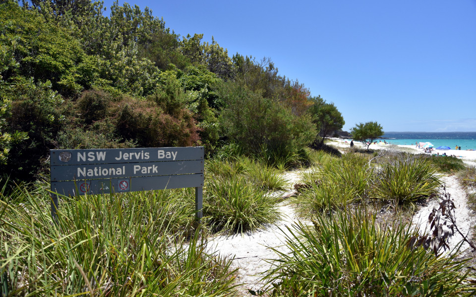Schilder des Jervis Bay Nationalparks, mit Blick auf den wei&szlig;esten Sandstrand der Welt von Hyams Beach und das t&uuml;rkisfarbene Meer.