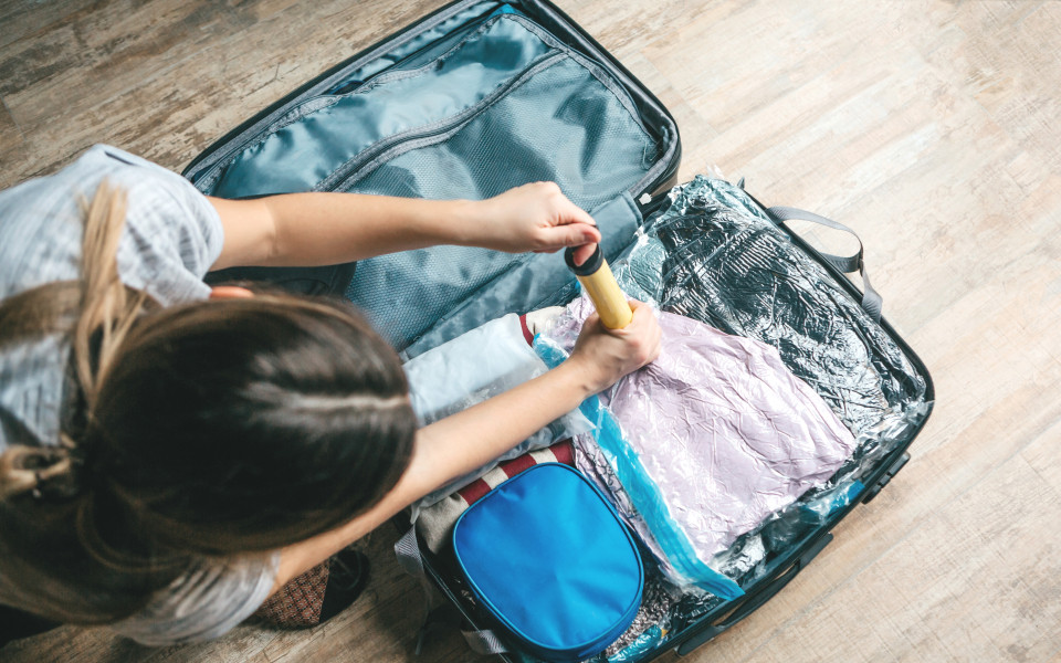 Frau vakuumiert Ihre Kleidung im Koffer, um Platz zu sparen 