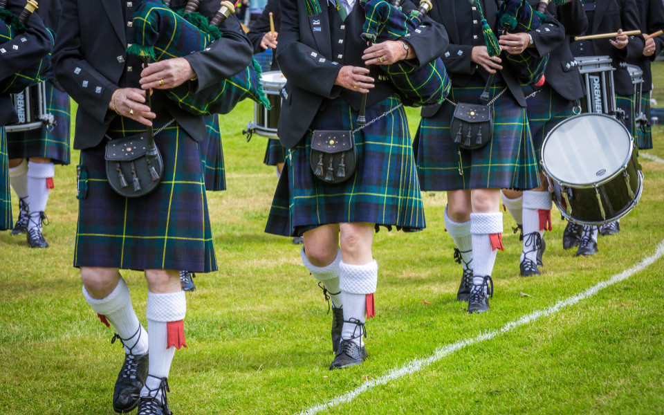 Schotten mit Kilt spielen auf einem Dudelsack