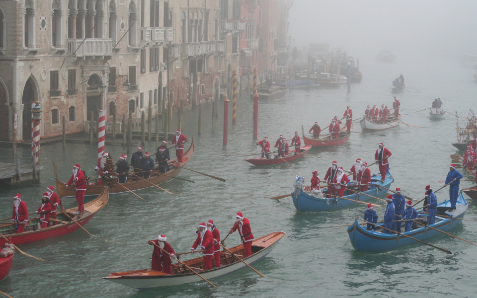 Gondeln voller als Nikolaus verkleideter Ruderer auf dem Canal Grande in Venedig bei winterlichem Nebel &ndash; traditionelle Nikolausfahrt in Italien.