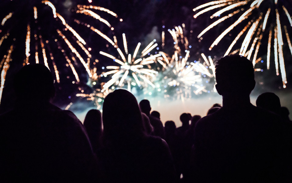 Menschen schauen in der Silvesternacht auf ein farbenfrohes Feuerwerk am Himmel &ndash; festliche Stimmung zum Jahreswechsel.