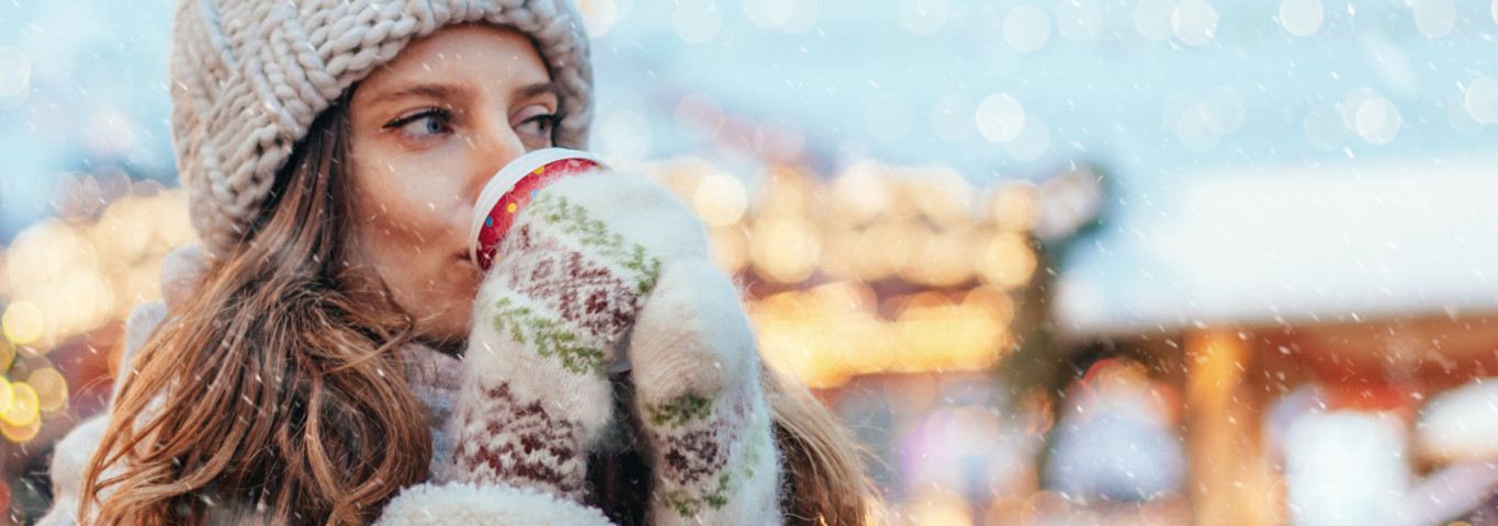 Frau trinkt Glühwein auf Weihnachtsmarkt