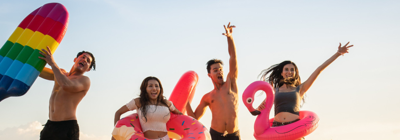 Familie mit Luftmatratzen springen am Strand in die Höhe